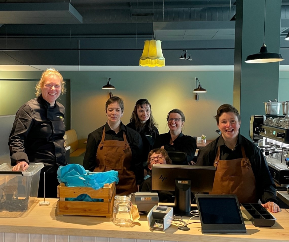 Een deel van het medewerkersteam van Tante Truus staat achter de balie in de lunchroom.
